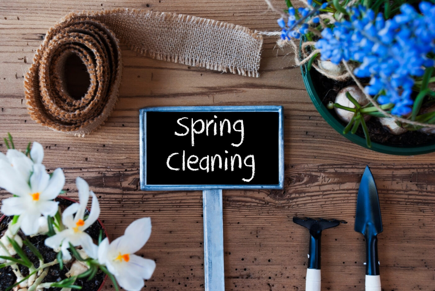 Office spring cleaning concept with flowers, tools, and sign on wooden surface