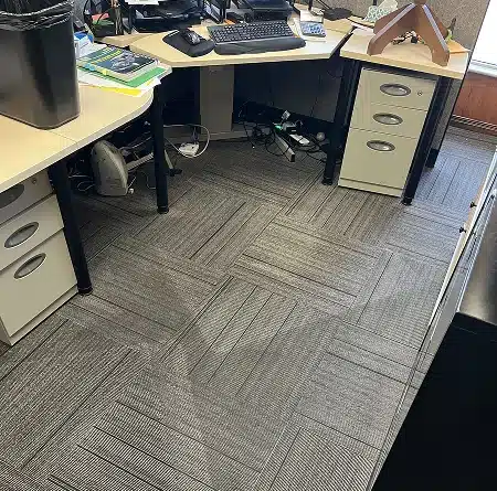 An office desk area showing patterned carpet tiles below.