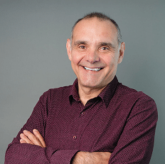 Headshot of a smiling man wearing a maroon button-down shirt.