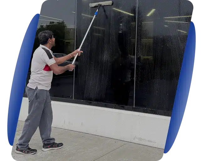 A person using a long extension pole squeegee to reach and wash high exterior windows.