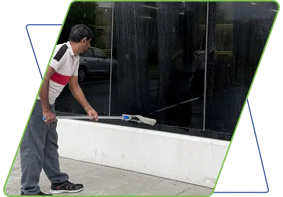 A window cleaner using a squeegee on the lower section of a large glass building exterior.